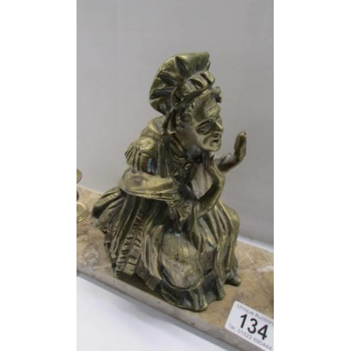 134 - A bronzed figure of and old lady on an marble base and with candleholders.