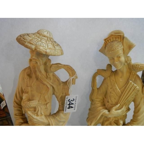 344 - A pair of tall resin oriental male and female figures.