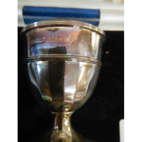 148 - A boxed silver egg cup, spoon and napkin ring set.