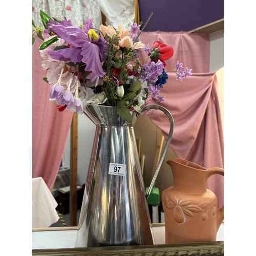 97 - A tall metal jug with artificial flowers & a terracotta jug