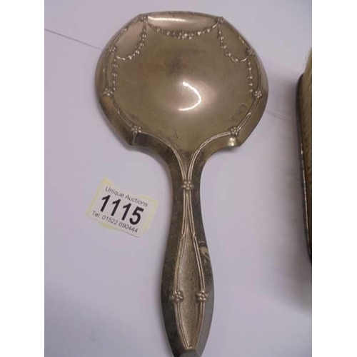 1115 - A silver hand mirror and a silver hair brush.