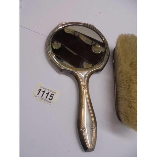 1115 - A silver hand mirror and a silver hair brush.