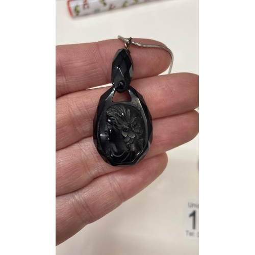 1086 - A Whitby jet pendent of a female profile together with a Amber heart pendant.