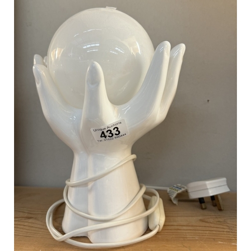 433 - A white glazed pottery pair of hands holding spherical glass shade table lamp. In working order