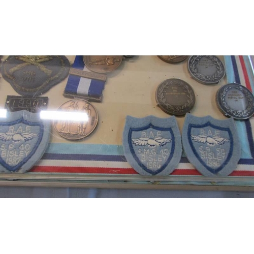 1134 - A cased collection of Royal Air Force Small Arms association medals and badges.