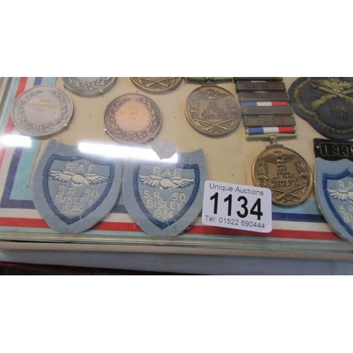 1134 - A cased collection of Royal Air Force Small Arms association medals and badges.