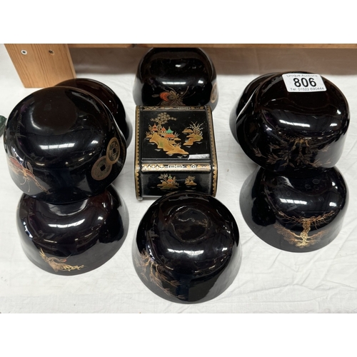 806 - A black lacquered ware jewellery box with 8 black bowls decorated with insects & trees etc.