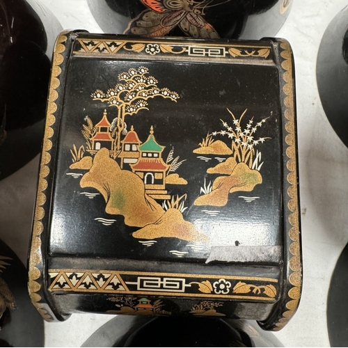 806 - A black lacquered ware jewellery box with 8 black bowls decorated with insects & trees etc.