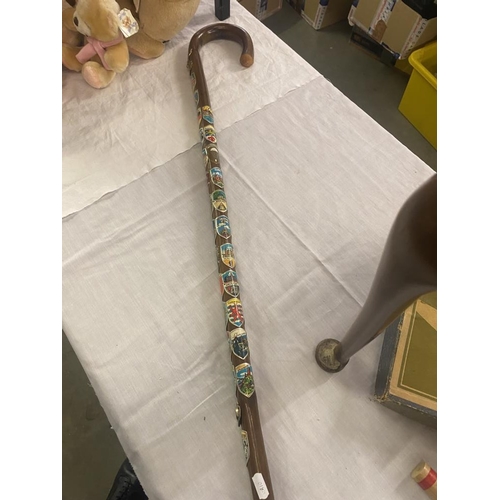 784 - A walking cane with a number of enamel badges attached