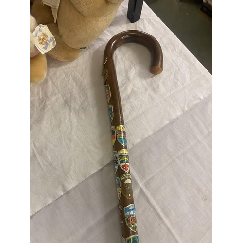 784 - A walking cane with a number of enamel badges attached