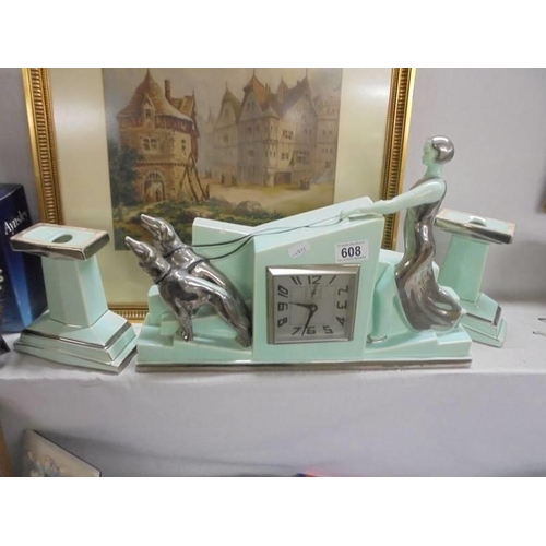 608 - An art deco three piece clock set featuring a lady in silver coloured dress and cap with two dogs.  ... 