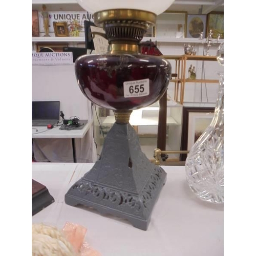 655 - A Victorian oil lamp on cast iron base and with ruby glass font. COLLECT ONLY.