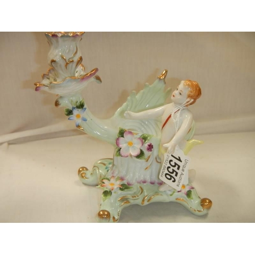 1556 - A continental porcelain candel holder featuring a cherub.