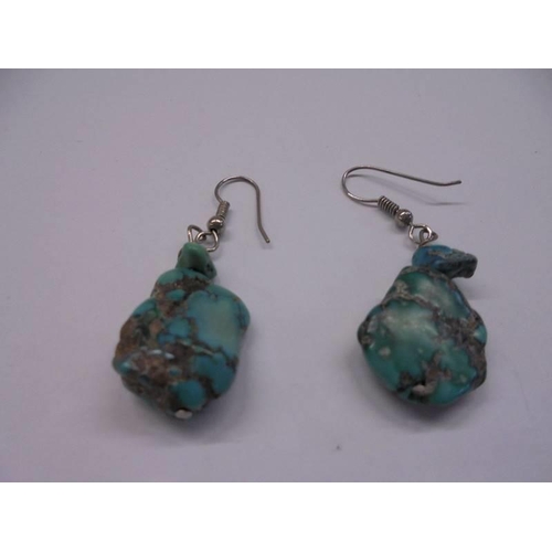 1085 - A pair of turquoise coloured drop earrings with silver coloured hooks.