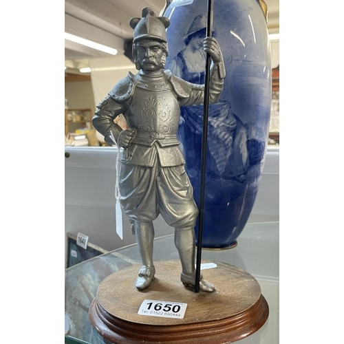 1650 - A spelter Knight in armour carrying a spear on wooden base