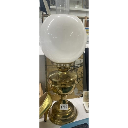 1702 - A brass oil lamp with plain white glass shade