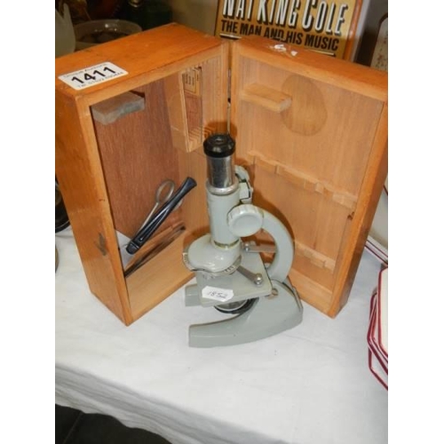 1411 - A cased student microscope.