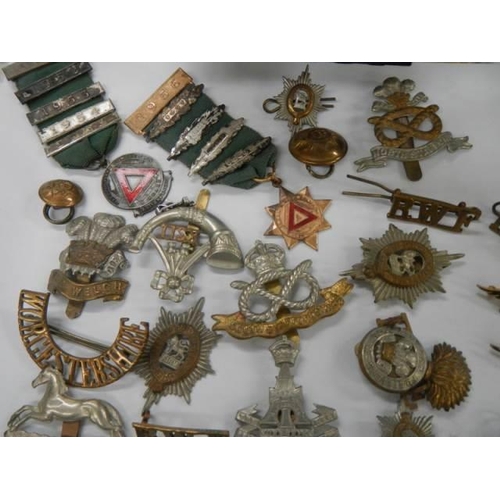 1582 - A quantity of military cap badges etc.,