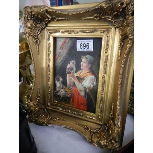 696 - A gilt framed overpainted print of a lady with kittens.