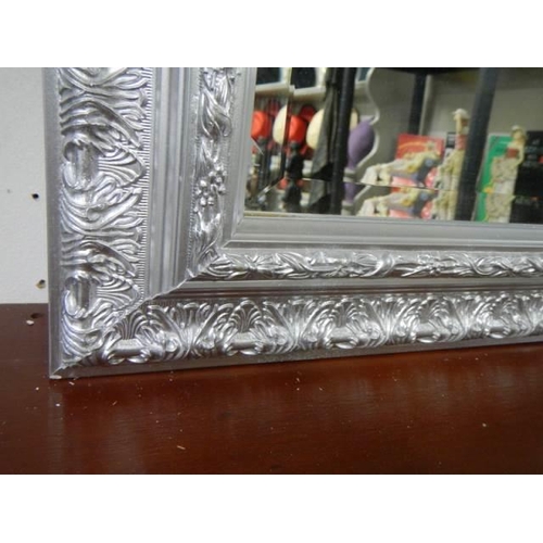 979 - A good bevel edged mirror in a silver coloured frame. COLLECT ONLY.