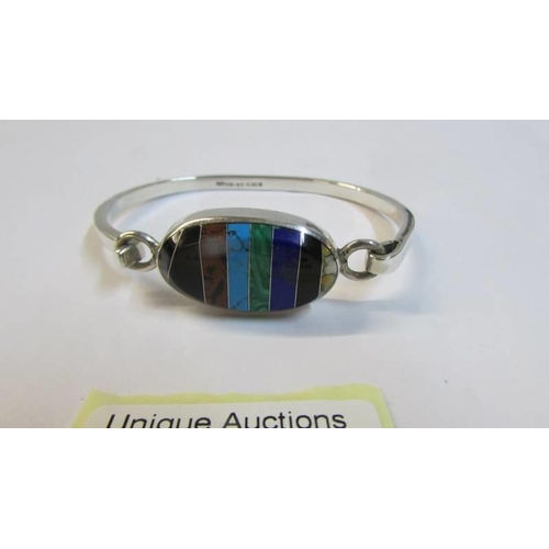 1087 - A silver bangle set with a large multi coloured stone,