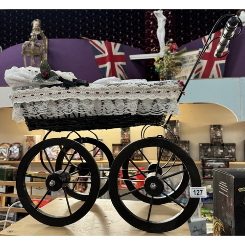 127 - A vintage style wicker dolls pram on wooden wheels