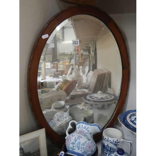 523 - An oak framed mid 20th century oval bevel edged mirror, COLLECT ONLY.