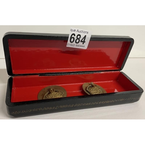 684 - A lacquered box with crown badges inside