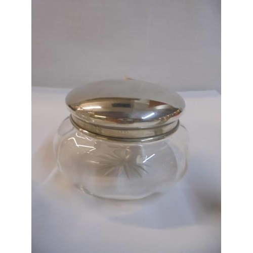 1141 - A silver pepperette, a silver topped scent bottle and a powder bowl with silver lid.