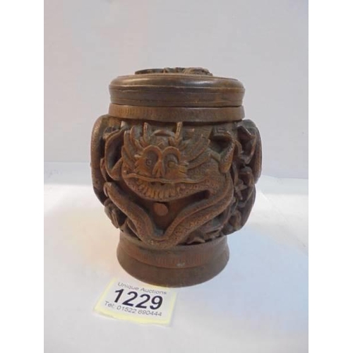 1229 - A Chinese carved wood tobacco jar, the lid having a regimental/royal crest.