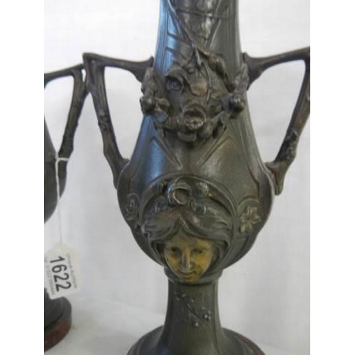 1622 - A pair of bronze vases featuring faces on both sides, 27 cm tall.