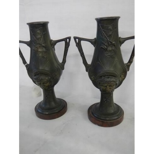 1622 - A pair of bronze vases featuring faces on both sides, 27 cm tall.