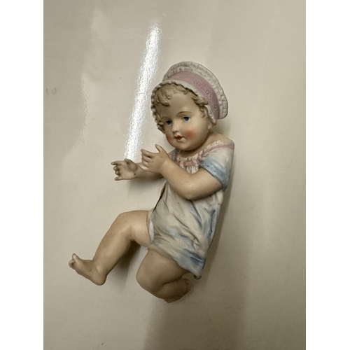 594 - A porcelain 'Piano' baby figure.