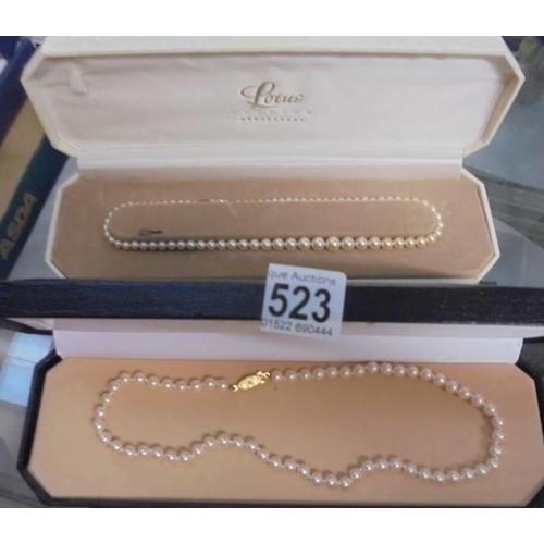 523 - Two cased rows of Lotus pearls.