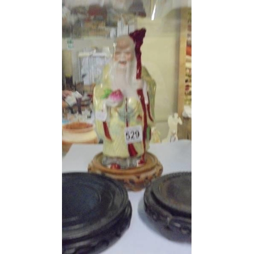 529 - A Chinese deity figure and three wooden bases.