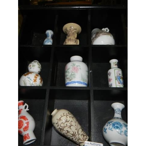 700 - A small display case with eleven minaiture Chinese style vases.