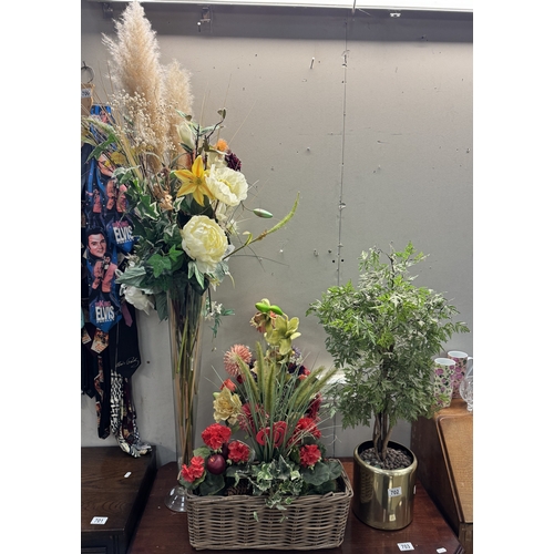 702 - A quantity of artificial plants & flowers in glass, brass & wicker vases / planters