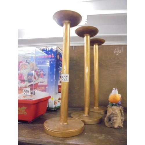 607 - Three tall gilded candlesticks.