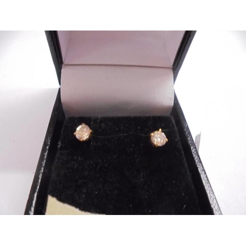 1002 - A pair of half carat diamond studs set in gold.