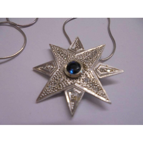 1003 - A white gold sapphire and diamond star pendant on a gold chain.