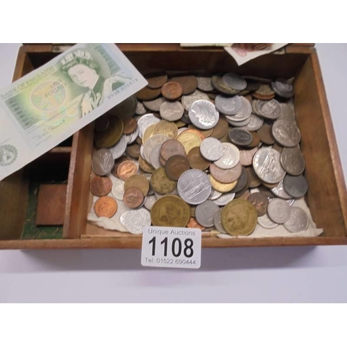 1108 - A wooden box of coins and bank notes.