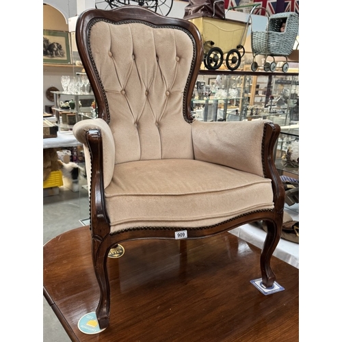 909 - An Edwardian mahogany framed deep buttoned wing arm chair