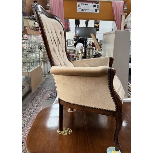 909 - An Edwardian mahogany framed deep buttoned wing arm chair