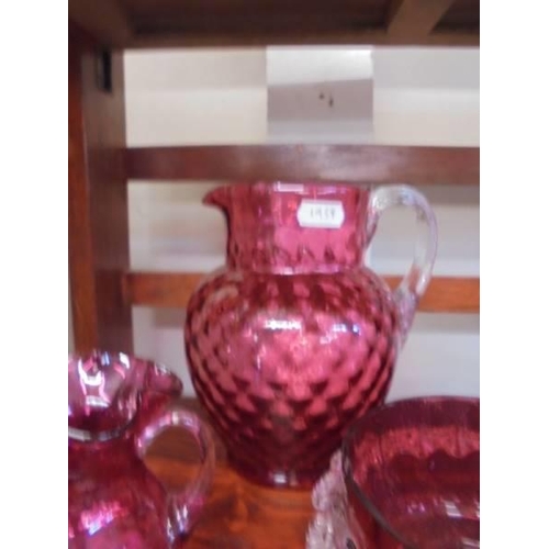 1280 - A cranberry glass water jug, sugar bowl and milk jug.