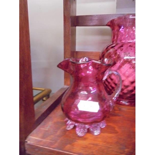 1280 - A cranberry glass water jug, sugar bowl and milk jug.