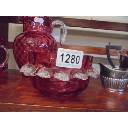 1280 - A cranberry glass water jug, sugar bowl and milk jug.