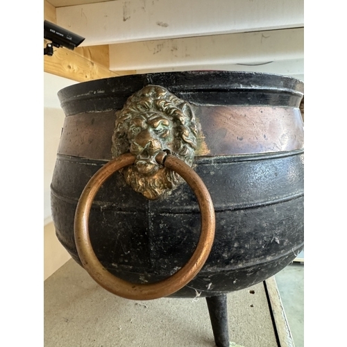 1167 - A large 19th century cast iron cauldron with copper band & lions head handles. Diameter approximatel... 