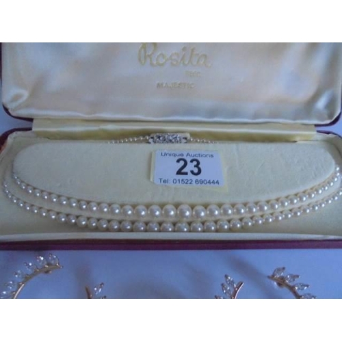 23 - A two strand pearl necklace together with a sparkly brooch and earrings.