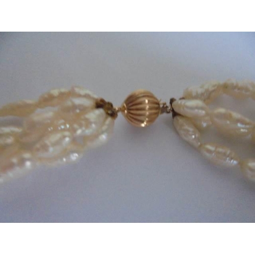 24 - A superb three strand natural pearl necklace with 14k gold clasp.