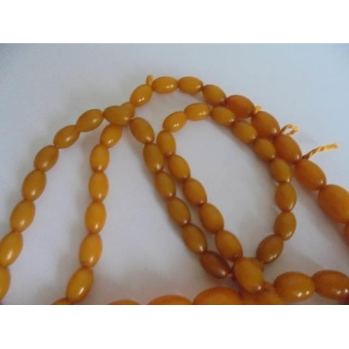 25 - A long graduated amber necklace.  51 grams in weight.